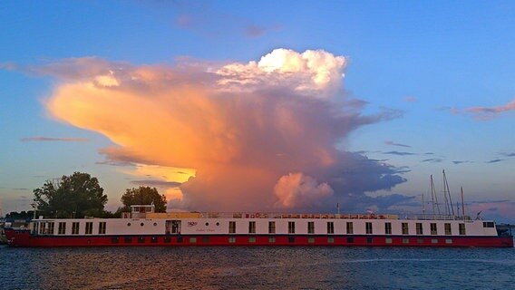 Blick auf ein Schiff mit sonnenbeschienener Wolke dahinter. © NDR Foto: Anja Mateblowski aus Berlin