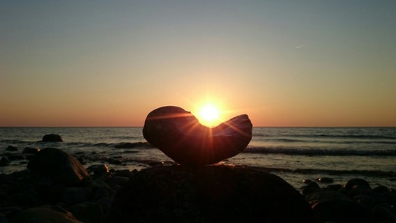 Sonnenuntergang geht an der Ostsee hinter einem herzförmigen Stein unter. © NDR Foto: Corinna Schaak aus Altenkirchen