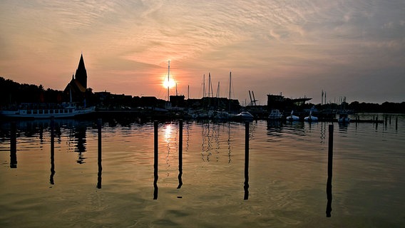 Die Sonne geht hinter einer Stadtsilhouette unter. © NDR Foto: Katrin Schäfer aus Blankenhagen