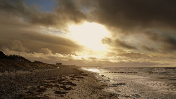 Am Strand von Hiddensee leuchtet die Sonne hinter dunklen Wolken hervor. © NDR Foto: Robert Ott von der Insel Hiddensee