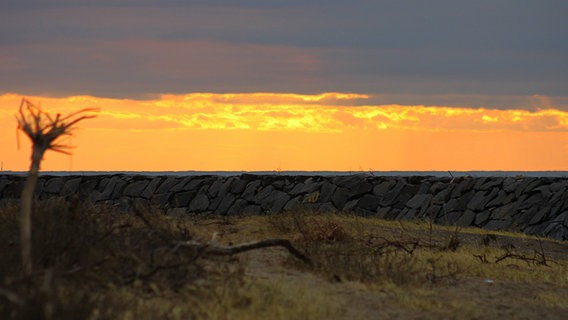Sonneuntergang hinter dunklen Wolken über der Huckemauer © NDR Foto: Gerald Schneider aus Kloster/Hiddensee