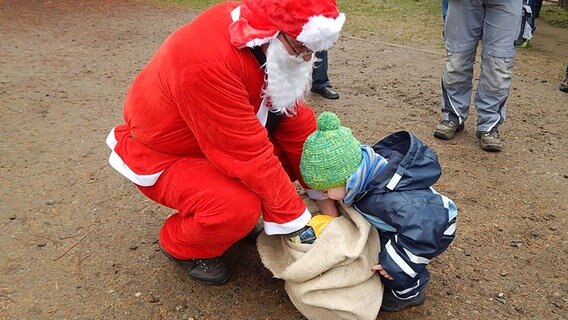 Ein kleiner Junge guckt dem Weihnachtsmann in den Sack mit den Geschenken. © NDR Foto: Ursula Pohl aus Schwerin