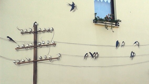 Wandbild zeigt Schwalben, die um Telegrafenmast fliegen. © NDR Foto: Jürgen Schmidt aus Parchim