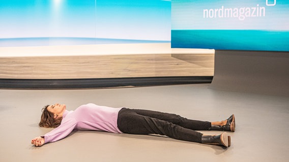 Nordmagazin Moderatorin Frauke Rauner liegt mit ausgestreckten Armen auf dem Boden. © NDR Foto: Georg Hundt