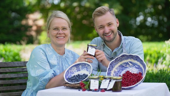 Elisabeth Neufeld-Picciani und Jan-Philipp Baumgart sitzen im Garten und halten ein Glas in den Händen. © NDR Foto: Paul Knoll