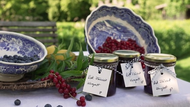 Glasses with berry compote stand on a table decorated with blueberries and currants.  © NDR Photo: Paul Knoll