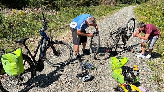 Pannen gehören auf einer Fahrradtour wohl dazu. Im Harz mussten Thomas Kempernolte (links) und Reporter Peter Jagla einen platten Reifen wechseln. © NDR/Friederike Castenow 