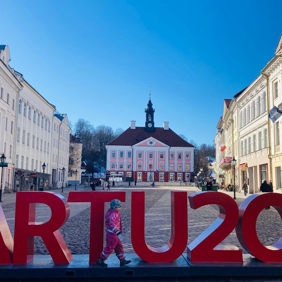 Ein mit weißen Fähnchen geschmückter Marktplatz auf dem ein roter Schriftzug steht "Tartu 2024". © Linnéa Kviske NDR 