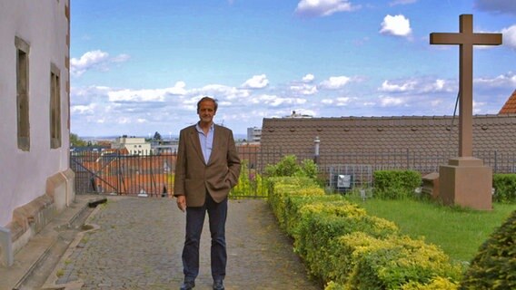 Florian Homm steht neben einem Kreuz.  
