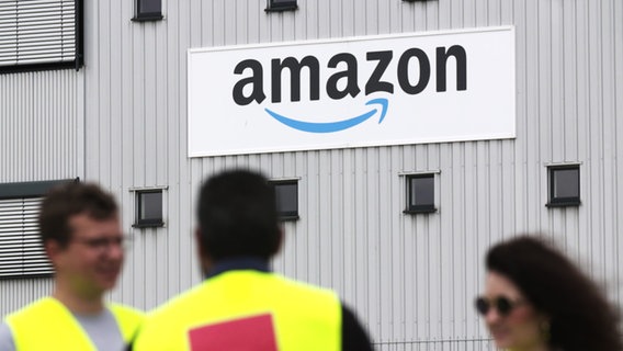 Menschen stehen vor einem Firmenschild von Amazon © NDR 