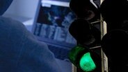 Eine auf "Grün" geschaltete Ampel in der Dunkelheit und ein Laptop © NDR 
