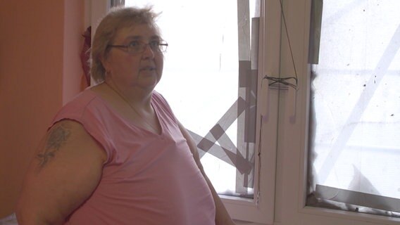 Heike Groth , Mieterin in einem Hochhaus im Bremer Stadtteil Tenever, steht vor ihrem beschädigten Fenster. Heike Groth , Mieterin in einem Hochhaus im Bremer Stadtteil Tenever, steht vor ihrem beschädigten Fenster. © NDR Foto: Screenshot