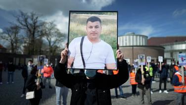 Eine Person hält ein Bild des verstorbenen Qosay K. in den Händen  