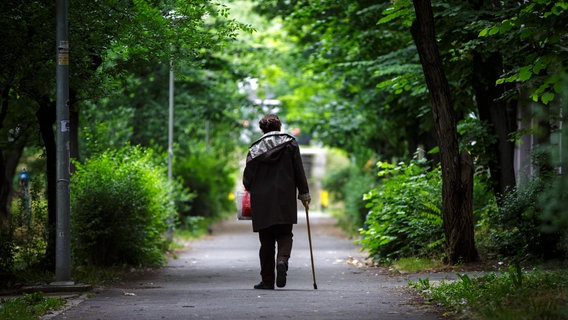 Eine ältere Frau geht auf einen Stock gestützt einen Weg entlang. © picture alliance/photothek Foto: Thomas Trutschel