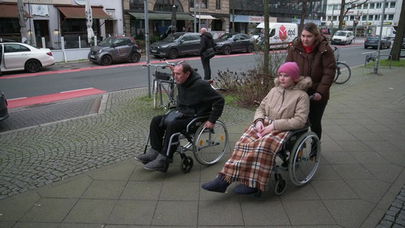 Svitlana, Yuri und Tochter Kira aus Charkiv werden in Deutschland behandelt. Vater und Tochter sitzen im Rollstuhl. © NDR 