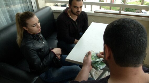 Der Schleuser Abu Suhaib bekommt von zwei Flüchtlingen ein Geldbündel. © NDR Foto: NDR