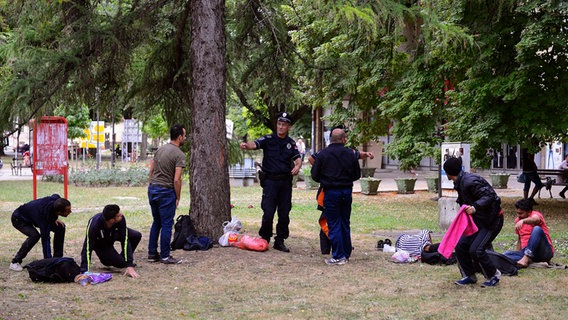 Ein serbischer Polizist vertreibt syrische Flüchtlinge aus dem Park einer serbischen Stadt in der der Nähe der ungarischen Grenze. © dpa/picture-alliance Foto: Edvard Molnar