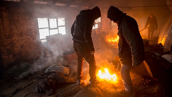 Flüchtlinge auf im Winter in Nord-Serbien: Um der Lebensgefahr durch die Kälte zu entfliehen werden in verlassenen Gebäuden offene Feuer entzündet, die eine neue Gefahrenquelle darstellen. © dpa/picture-alliance Foto: Szilard Koszticsak