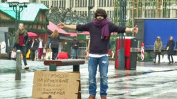 Ein Mann mit verbundenen Augen steht in der Hamburger Innenstadt. Auf einem Schild steht: "Ich bin Moslem. Ich bin kein Terrorist. Ich vertraue Dir - vertraue mir und umarme mich." © NDR 