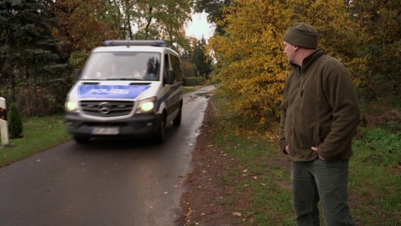 Jäger Enrico Mathe (re.) blickt einem Polizeifahrzeug an der deutsch-polnischen Grenze hinterher. © NDR 