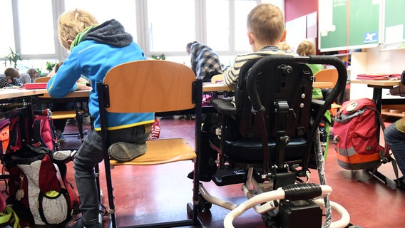 Zwei Schulkinder, eins davon im Rollstuhl sitzend, an einem Schultisch. © picture alliance/dpa Foto: Maurizio Gambarini