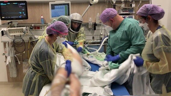 Pflegekräfte stehen in Schutzkleidung an einem Patientenbett © NDR Foto: Screenshot