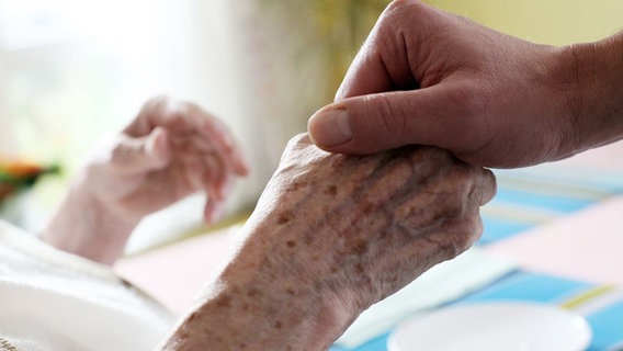 Eine Pflegerin hält die Hand einer alten Frau © dpa Foto: Oliver Berg