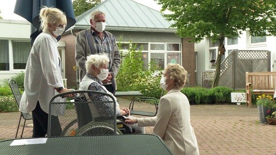 Vier ältere Personen, eine davon im Rollstuhl sitzend, in einem Pflegeheim. © NDR Foto: Screenshot