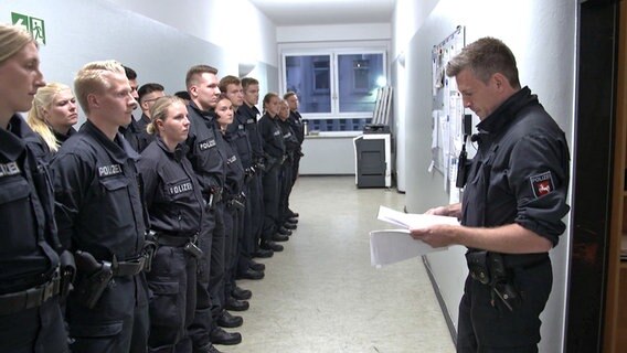 Hendrik Steckhan (r.) von der Polizei Hannover und seine 25 KollegInnen bei einer Einsatzbesprechung. © NDR Foto: Screenshot