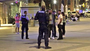 Zwei Polizisten stehen vor dem Bahnhof in Hannover vor zwei Männern mit Migrationshintergrund. © NDR Foto: Screenshot