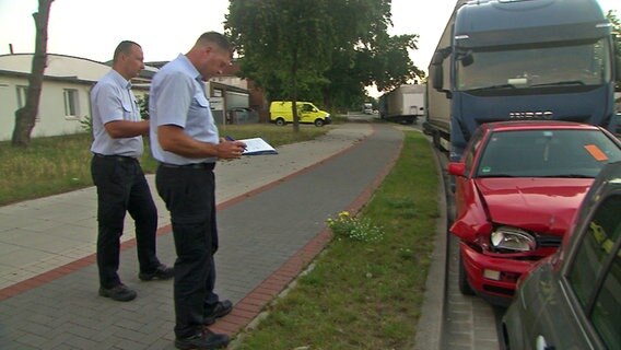 Müllfahnder Daniel Borchardt (l.) und Stefan Hencke schreiben ein Auto auf. © NDR Foto: Screenshot