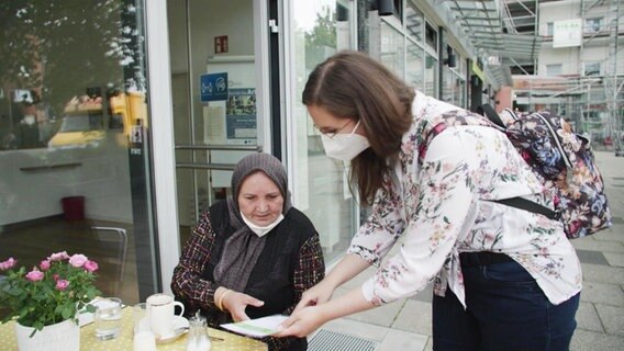 Gesundheitsfachkraft Esra Aksoy kümmert spricht in Bremen mit einer Frau im Café.  