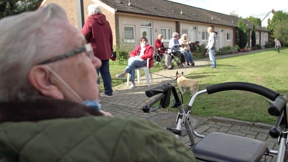 Senioren sitzen und stehen vor einer Wohnanlage in Osnabrück. © NDR Foto: Screenshot