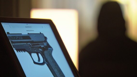 Schusswaffe der Firma Sig Sauer, im Hintergrund ein verdeckter Informant. © NDR 
