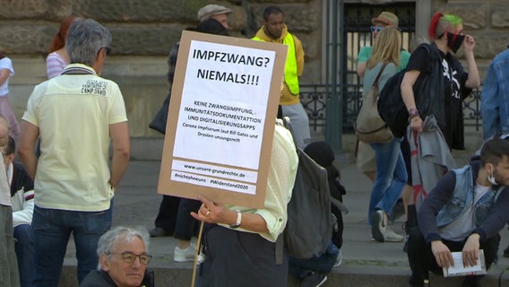 Demonstrant gegen die Corona-Maßnahmen in Hamburg mit Plakat gegen Impfmaßnahmen © NDR Foto: Screenshot