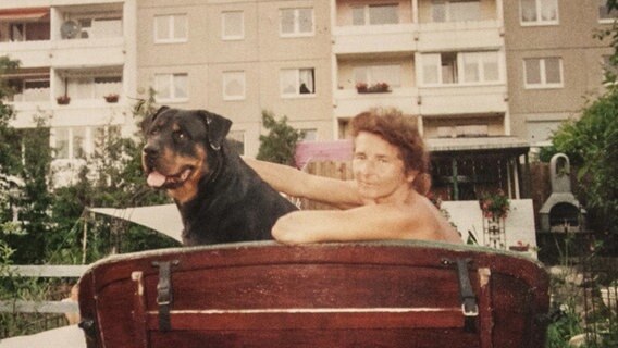 Frau mit Hund auf einer Bank.  