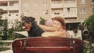 Frau mit Hund auf einer Bank.  