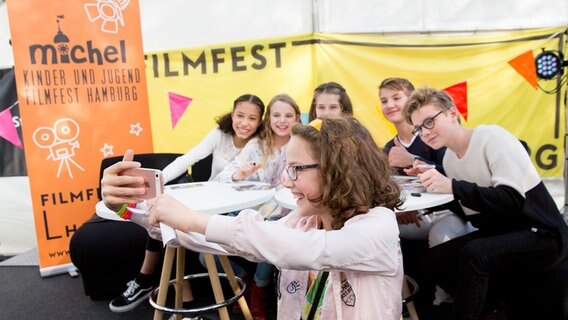 Emma Roth, Emilia Flint, Marleen Quentin, Luke Matt Röntgen und Ruben Storck hinter einem Fan mit Handy. © NDR Foto: Claudia Timmann