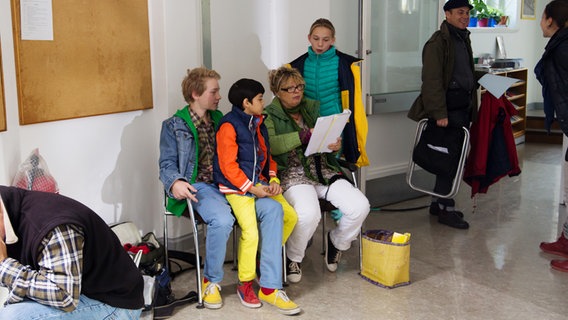 Max und Luis sitzen neben einer Frau die ein Script in der Hand hält. Jessi schaut ihr über die Schulter. © NDR Foto: Claudia Timmann