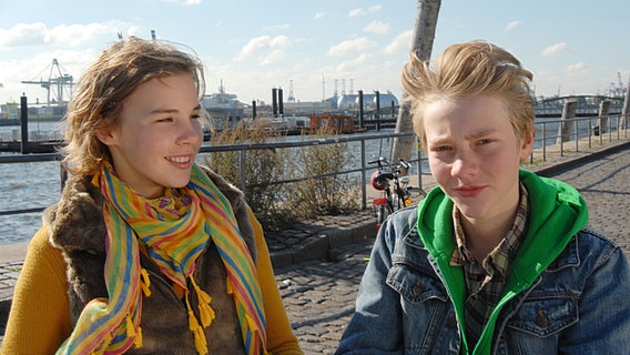 Tatja (Maya Frantzius) steht neben Max (Bruno Alexander) am Hafen und lächelt ihn an. © NDR/Studio Hamburg Foto: Romano Ruhnau