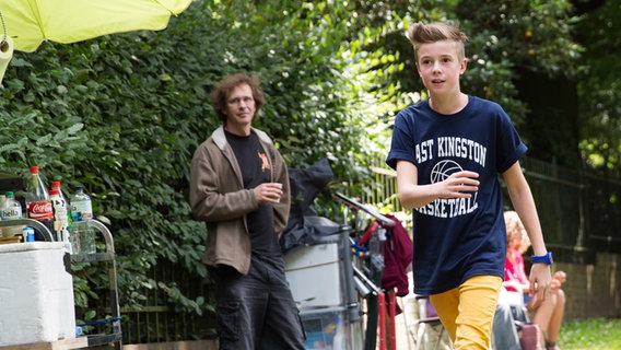 Niklas (Jaden Dreier) geht auf dem Bürgersteig.  Im Hintergrund steht ein Lichttechniker. © NDR Foto: Claudia Timmann