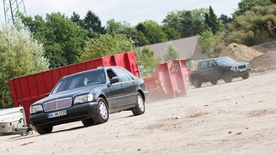 Zwei Autos kurven durch die Kiesgrube. Staub wirbelt auf. © NDR Foto: Claudia Timmann