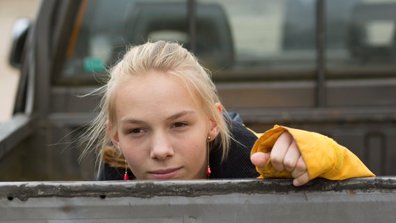 Jessi (Martha Fries) lugt über die Heckklappe eines Pick Ups. © NDR Foto: Claudia Timmann