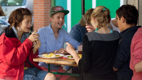 Die Pfefferkörner Niklas (Jaden Dreier), Jessi (Martha Fries), Ceyda (Merle de Villiers) und Anton (Danilo Kamber) sitzen zusammen am Tisch. © NDR Foto: Claudia Timmann