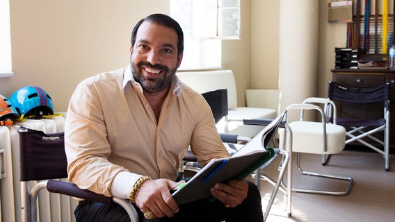 Serkan Cetinkaya sitzt mit einem Buch in der Hand auf einem Stuhl. © NDR Foto: Claudia Timmann