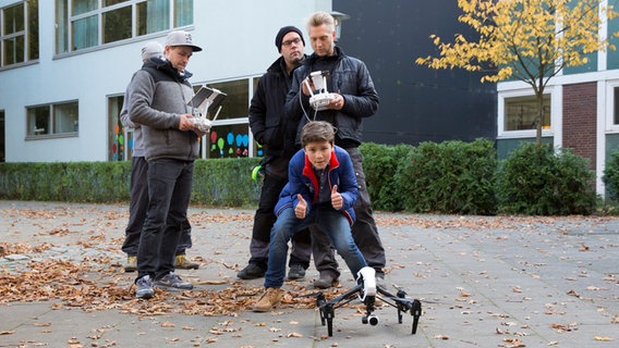 Ramin (Jann Piet) und das Filmteam stehen vor einer Drohne. © NDR Foto: Claudia Timmann