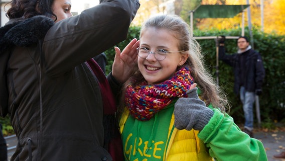 Pinja (Sina Michel) bekommt ihre Haare gerichtet und macht eine "Daumen hoch"-Geste in die Kamera. © NDR Foto: Claudia Timmann
