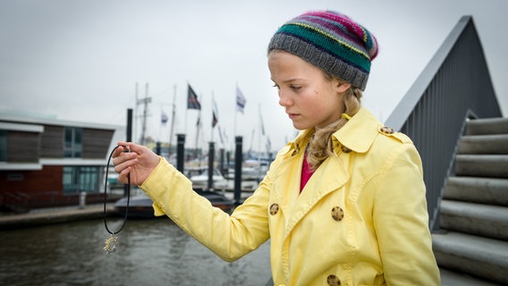 Stella (Zoë Malia Moon) hält eine Kette in der Hand. © NDR/Studio HH Foto: Boris Laewen