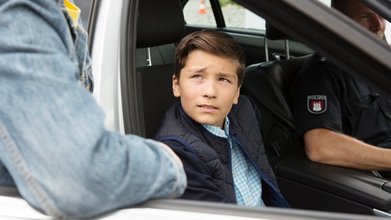 Ramin (Jann Piet) sitzt auf dem Beifahrersitz im Polizeiauto. © NDR Foto: Claudia Timmann