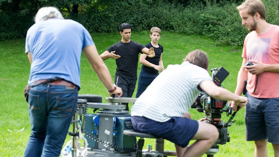 Hamet (Altamasch Noor) und Johannis (Luke Matt Röntgen) und davor sieht man das Kamerateam in der Unschärfe. © NDR Foto: Claudia Timmann